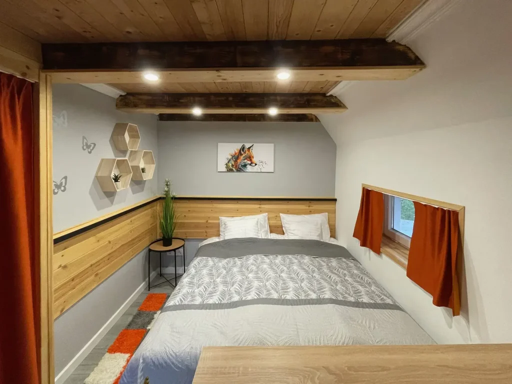 Hálószoba fagerendás mennyezettel és hangulatvilágítással a Calm Resort Fox apartmanjában